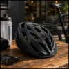 Black adult bike helmet with multiple ventilation vents and visor on a wooden table