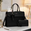 Black leather laptop tote bag for women with a matching wristlet pouch, large tumbler, and adjustable shoulder strap displayed on a modern office desk.