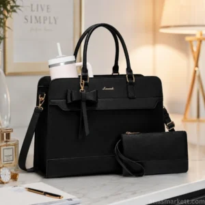Black leather laptop tote bag for women with a matching wristlet pouch, large tumbler, and adjustable shoulder strap displayed on a modern office desk.